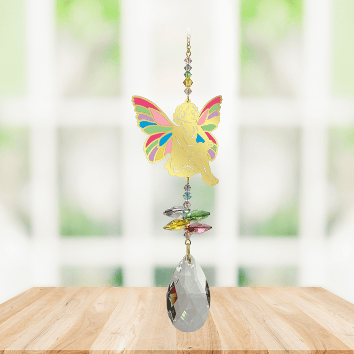 Sitting Fairy confetti Window Jewels crystal suncatcher hanging in a bright window, mirror-gold fairy motif with colourful crystals and clear drop.