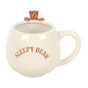 Front view of rounded ceramic Sleepy Bear mug showing text and bear peeking out.
