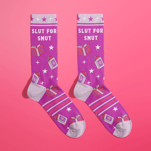 Pair of purple women’s novelty crew socks with lilac accents, star pattern and cheeky Slut For Smut text with romance book graphics.