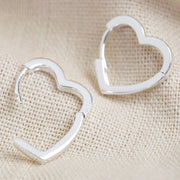 Silver heart hoop earrings shown with hinged click fastening open to display the easy wear mechanism.