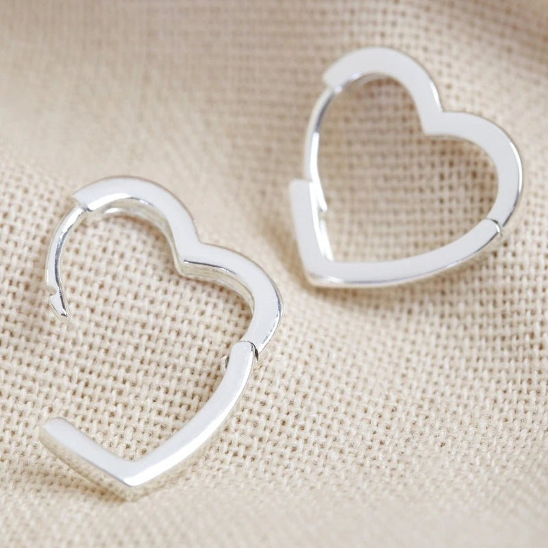 Silver heart hoop earrings shown with hinged click fastening open to display the easy wear mechanism.