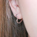 Side view of a polished silver heart hoop earring hugging the ear for a simple everyday look.