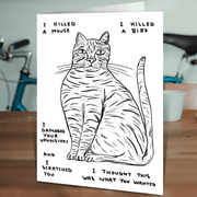 David Shrigley cat card on a wooden table in a lifestyle scene.

