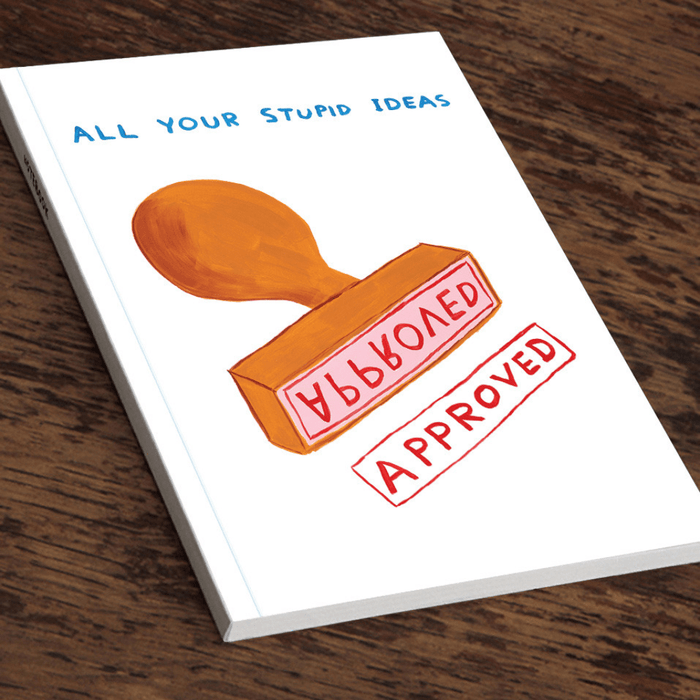 Angled view of David Shrigley “All your stupid ideas” A5 notebook on a wooden table.

