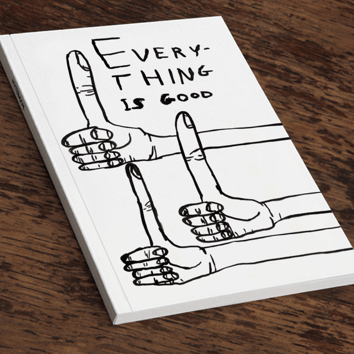 Angled view of David Shrigley “Everything is good” A5 notebook on a wooden table.

