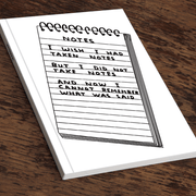 Angled view of David Shrigley “Wish I’d Taken Notes” A5 notebook on a wooden table.

