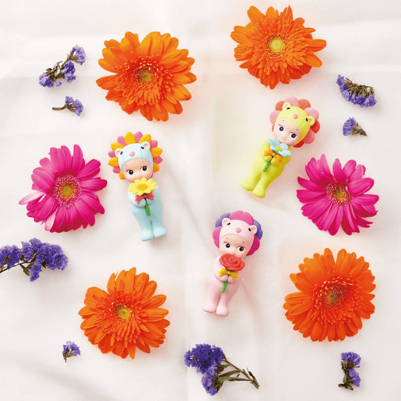 Three Sonny Angel Flower Gift figures displayed among colourful flowers