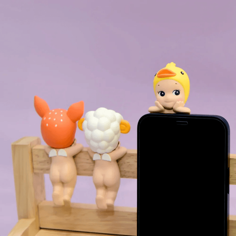 Duck, Sheep and Fawn Sonny Angel Hippers displayed on a phone and wooden rail