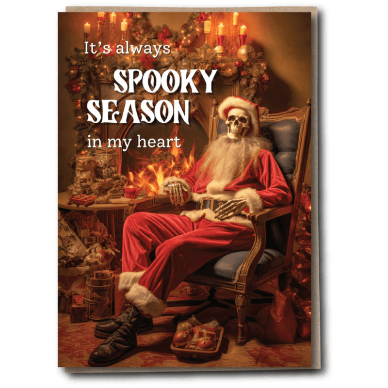 Spooky Christmas card with skeleton Santa by the fire and wording about spooky season in my heart.