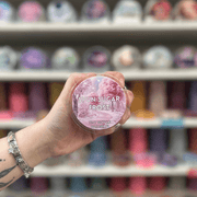 Spun Sugar Frost wax melt pot held in hand with colourful wax melts softly blurred behind