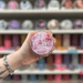 Spun Sugar Frost wax melt pot held in hand with colourful wax melts softly blurred behind