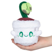 Front view of Squishable Ghost Plant plush with white pot, green stem and skull-shaped leaf, held in hand