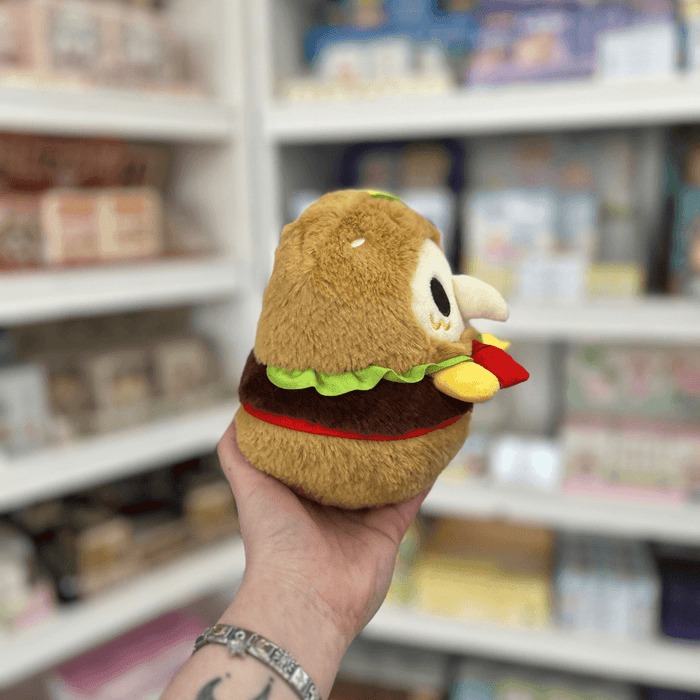 Profile view of Squishable Alter Egos Plague Doctor Burger plushie showing its fluffy bun, plague mask and burger filling details