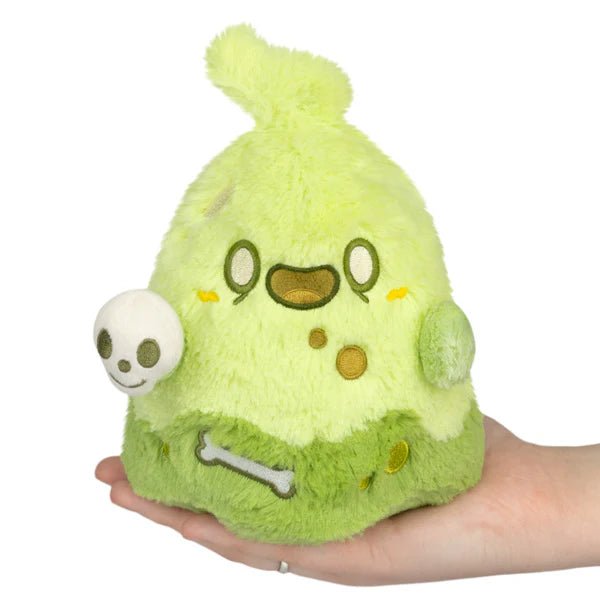 Front view of Squishable Slime Ghost plush in neon green with skull accessory, held in hand