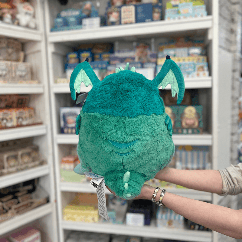 Squishable Baby Cthulhu plush toy held in hands in a gift shop, back view showing wings and tail