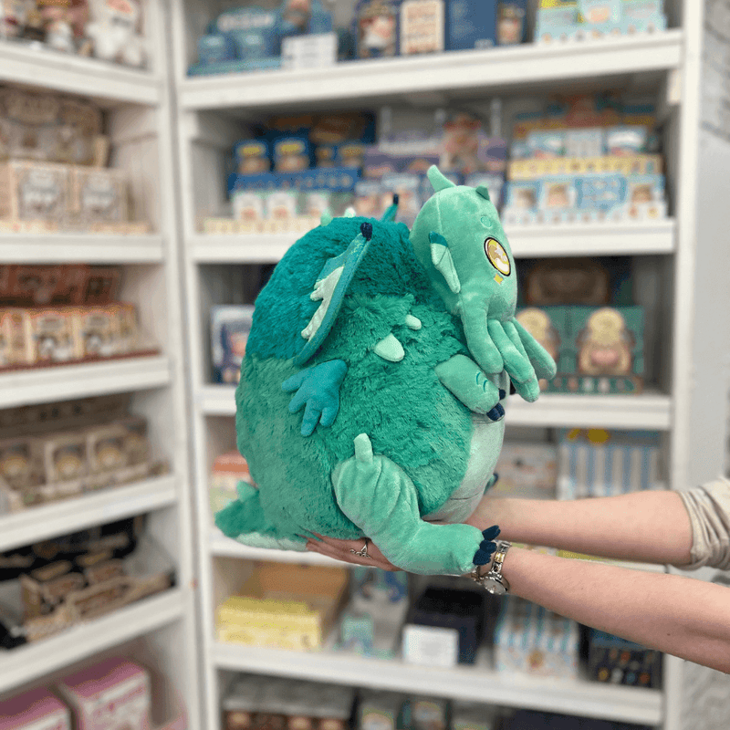 Squishable Baby Cthulhu plush toy held in hands in a gift shop, side view