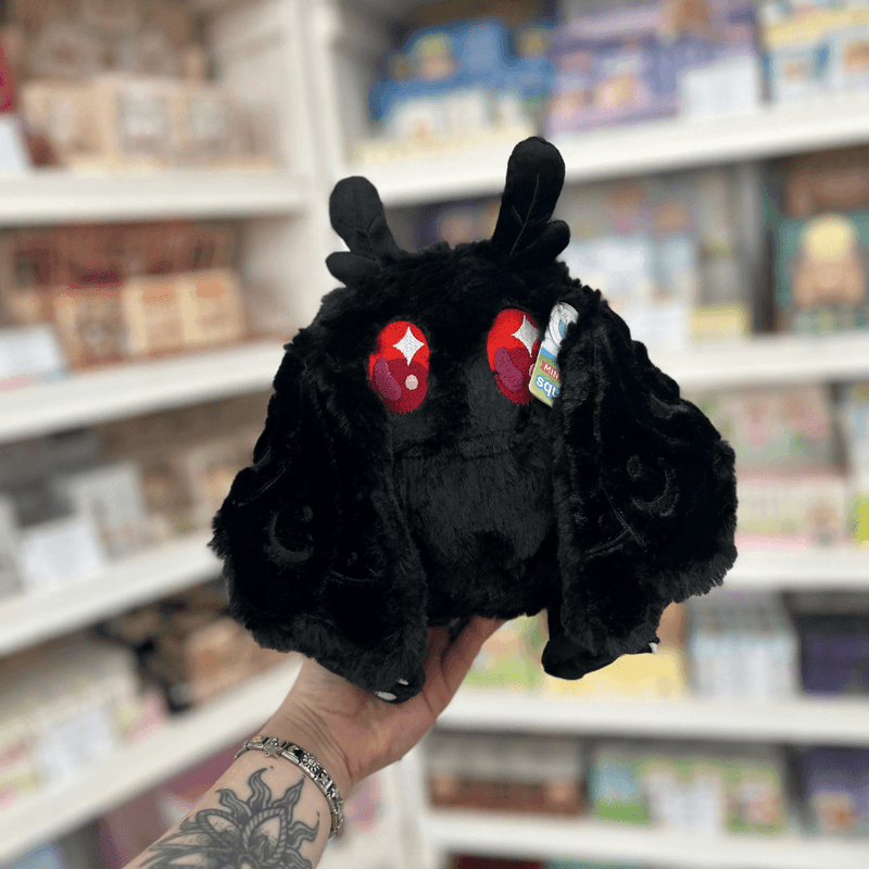 Mini Squishable Baby Mothman black plushie front view with red eyes, tiny feet and soft moth-like wings