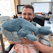 Person holding the Squishable Blue Whale plush toy to show its large, cuddly size
