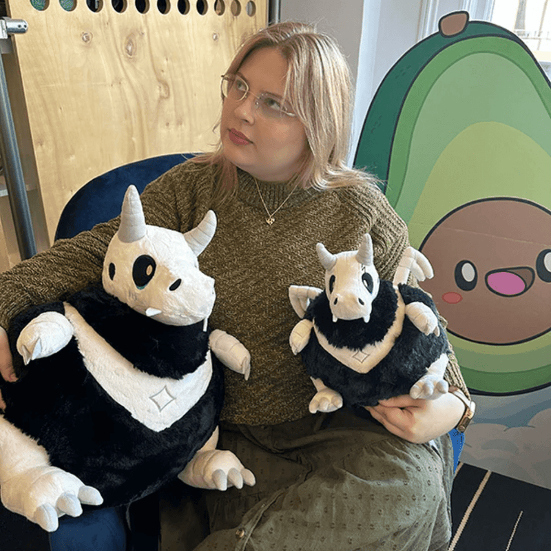 Person holding Mini Squishable Bone Dragon plush beside a larger Bone Dragon plush