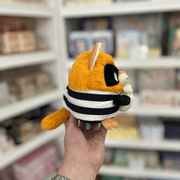 Side view of Squishable Alter Egos Cat Burglar Kitty plushie showing its striped burglar outfit, orange tail and money bag