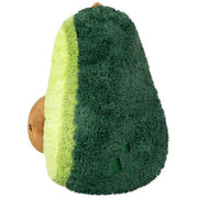 Side view of the Squishable Comfort Food Avocado plushie showing soft gradient layers from green to yellow and plush seed detail.

