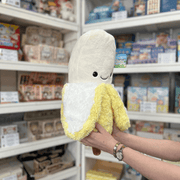 Squishable Comfort Food Banana plush toy angled view held in hands in a shop