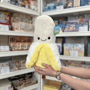 Squishable Comfort Food Banana plush toy front view held in hands in a shop