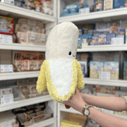 Squishable Comfort Food Banana plush toy side view held in hands in a shop