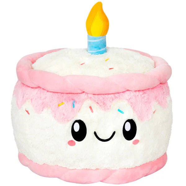  Front view of the Squishable Birthday Cake plushie with a happy face, pink icing, and plush candle.