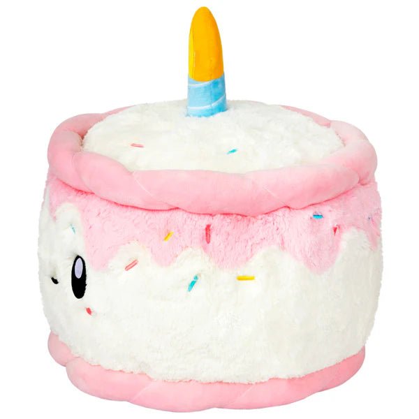 Side view of the Squishable Birthday Cake plushie with layered white and pink icing and a soft flame-topped candle.