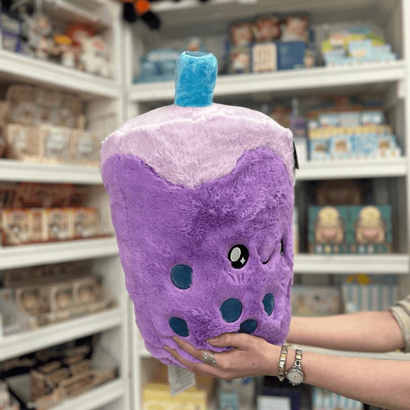 Squishable Comfort Food Bubble Tea plush toy held in hands in a gift shop, angled side view