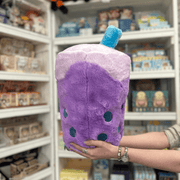 Squishable Comfort Food Bubble Tea plush toy held in hands in a gift shop, side view