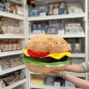 Squishable Comfort Food Cheeseburger plush toy held in hands in a gift shop, angled side view