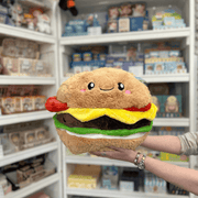 Squishable Comfort Food Cheeseburger plush toy held in hands in a gift shop, front view