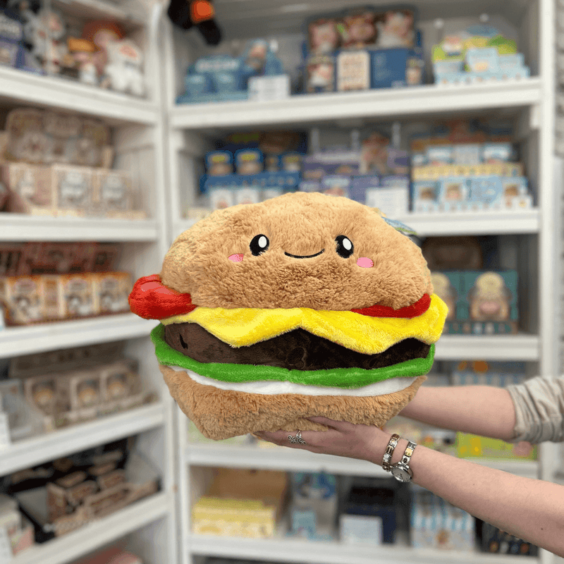 Squishable Comfort Food Cheeseburger plush toy held in hands in a gift shop, front view