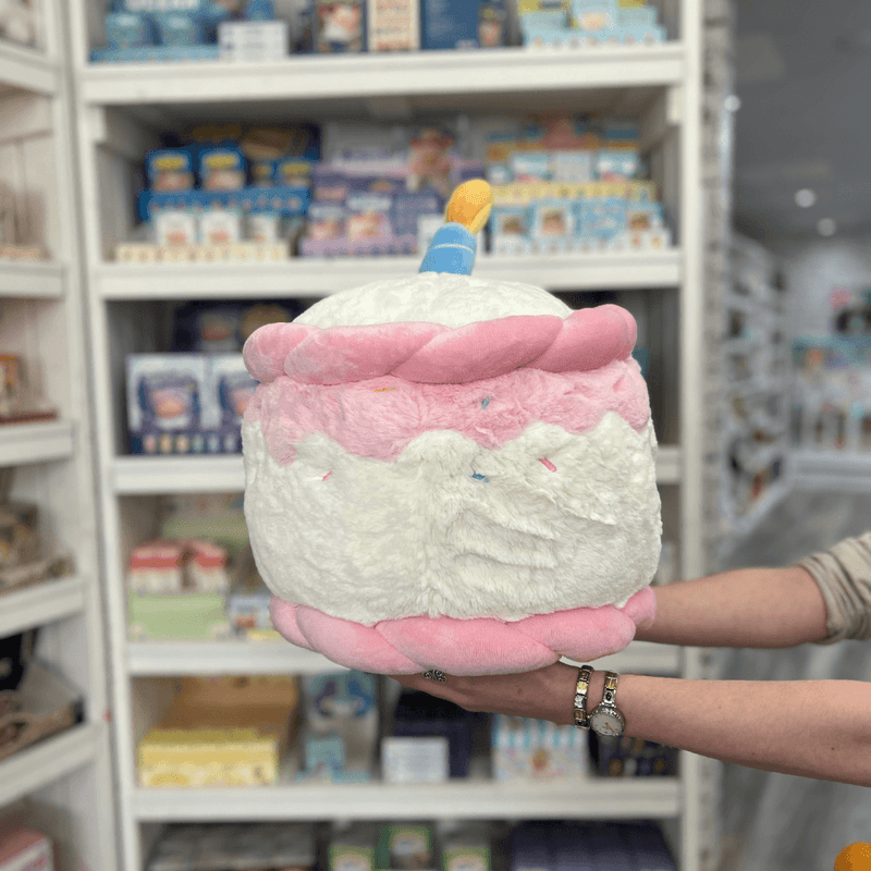Squishable Comfort Food Happy Birthday Cake plush toy held in hands in a gift shop, back view