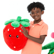 Child holding a large Squishable Comfort Food Strawberry plush toy with green leaves