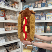 Squishable Dachshund Hot Dog plush toy back view showing bun and ketchup detail held in hands in a shop