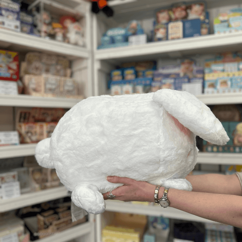 Squishable Fluffy Bunny plush toy side view held in hands in a shop