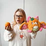 Person holding an orange and Mini Squishable Fruit Bat plush with pink wings