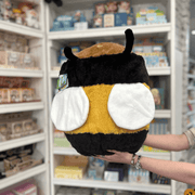 Squishable Fuzzy Bumblebee plush toy held in hands in a gift shop, back view showing wings