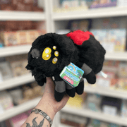 Mini Squishable Black Widow plush toy held in hand in a gift shop, side view
