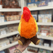 Mini Squishable Campfire plush toy held in hand in a gift shop, back view