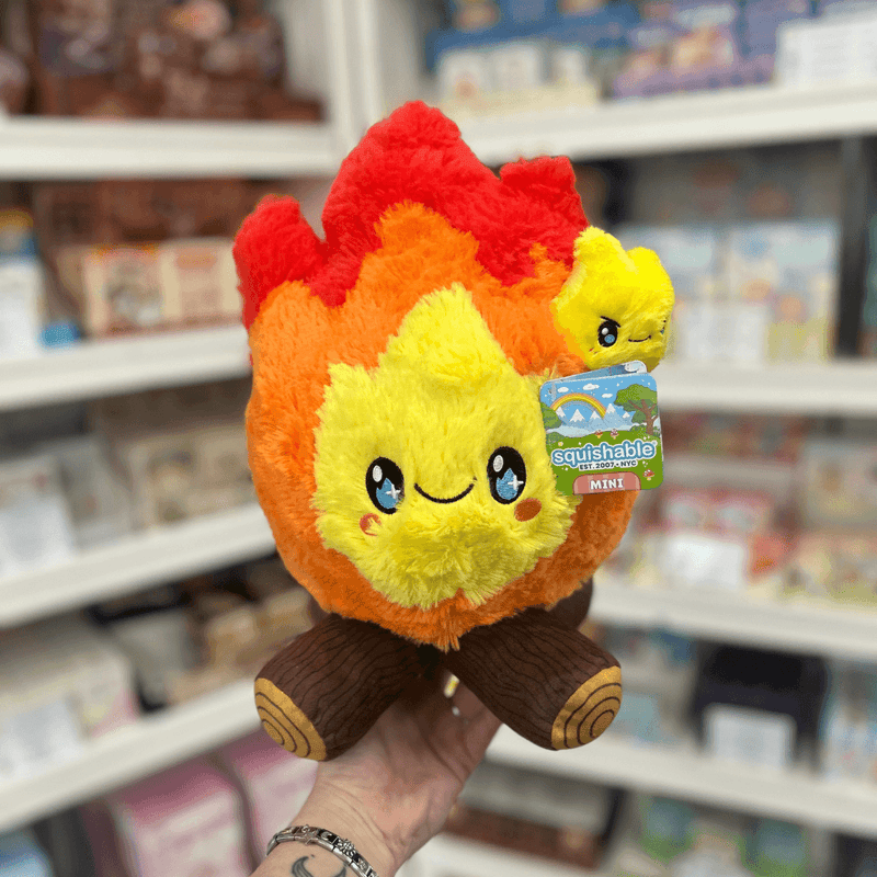 Mini Squishable Campfire plush toy held in hand in a gift shop, front view