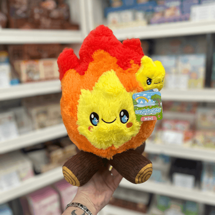 Mini Squishable Campfire plush toy held in hand in a gift shop, front view