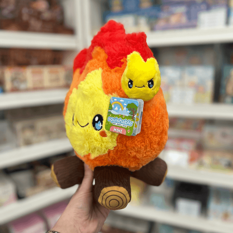 Mini Squishable Campfire plush toy held in hand in a gift shop, side view