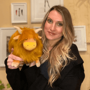 Woman holding a golden Squishable Mini Highland Cow plush toy