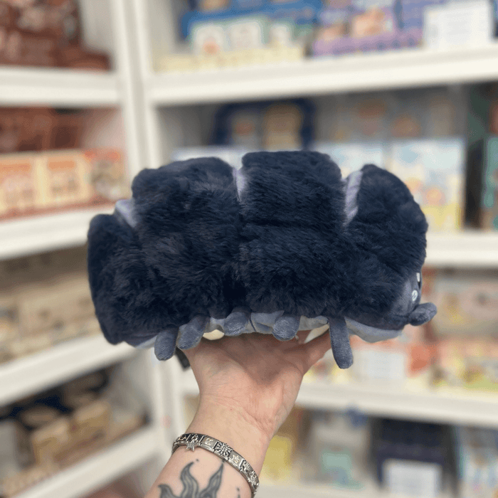 Mini Squishable Pillbug Rollie Pollie plush toy held in hand in a gift shop, back view showing segmented body