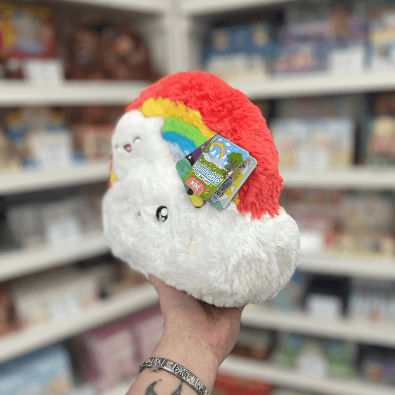 Mini Squishable Rainbow plush toy held in hand in a gift shop, back view