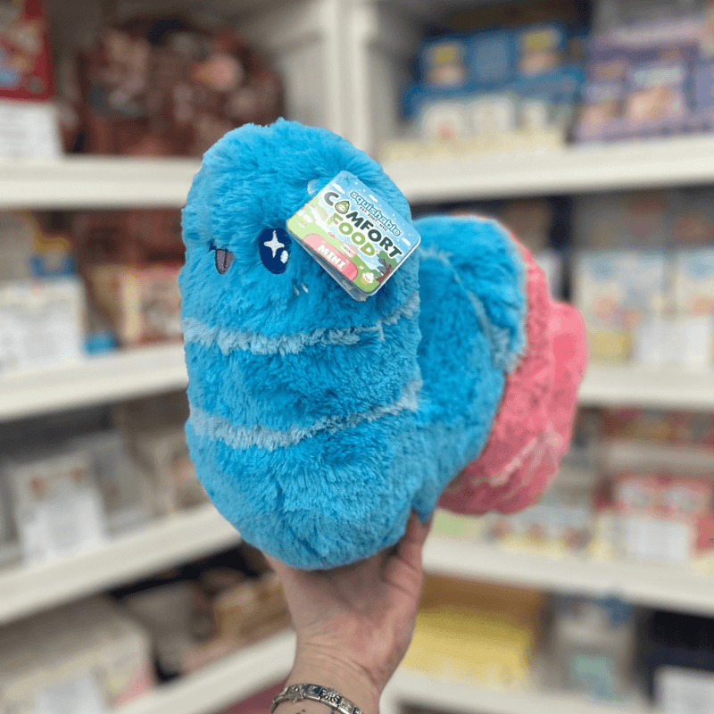 Mini Squishable Sour Gummy Worm plush toy held in hand in a gift shop, side view